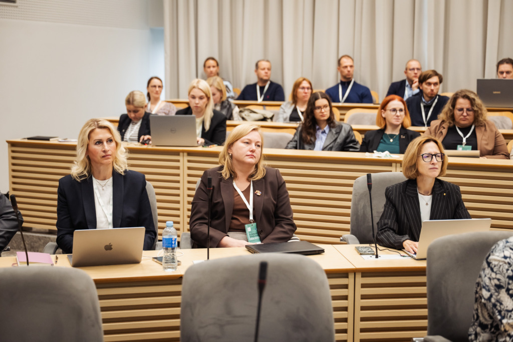 Participants at the SustAInLivWork Annual Summit 2026 listen to a presentation on data infrastructure and AI solutions. Attendees sit throughout the conference room while a speaker presents at the front.